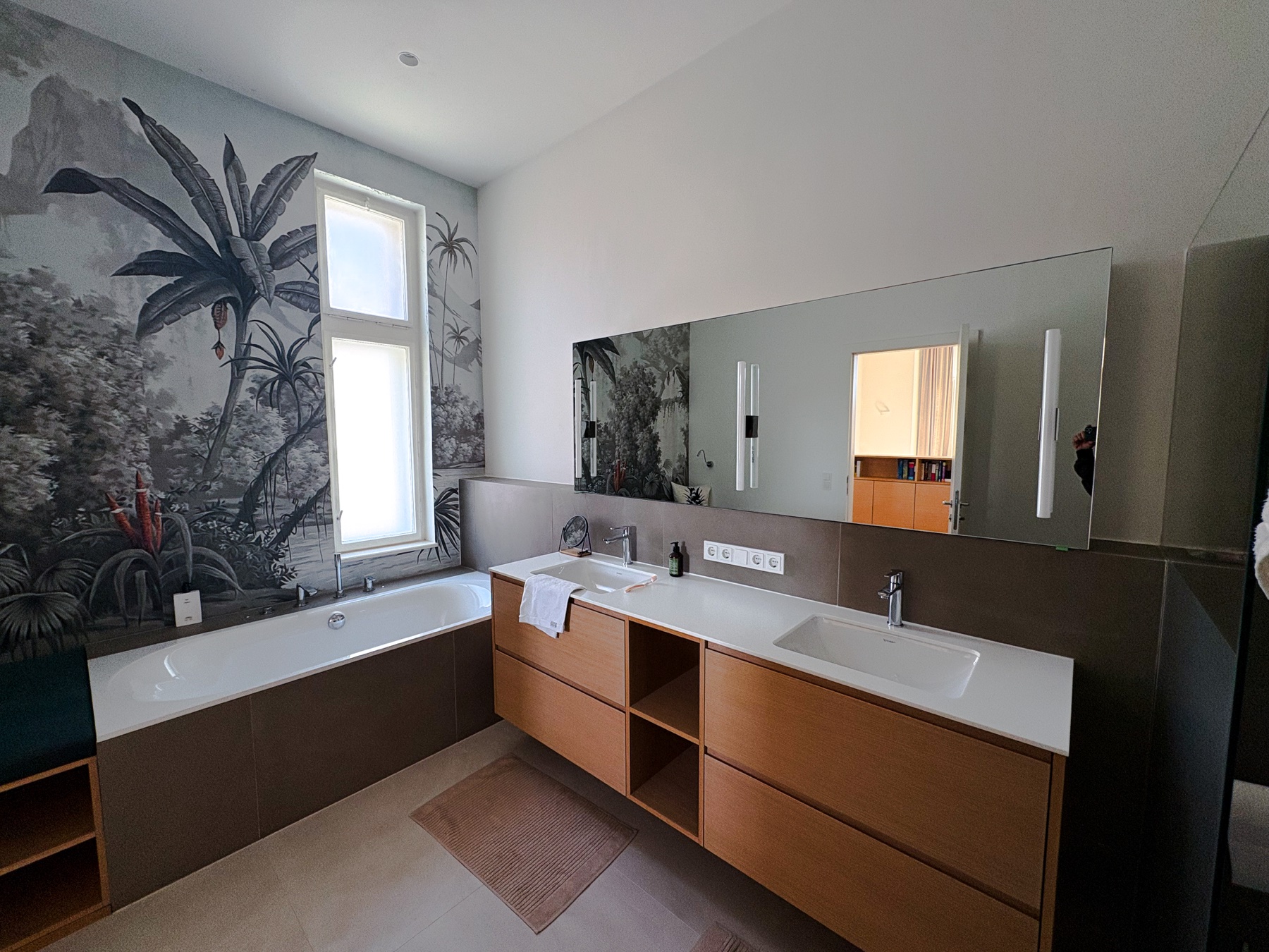 Badezimmer mit großem Wandspiegel, Doppelwaschtisch und Badewanne